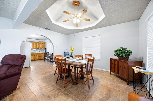 2309 W Chapin St, Edinburg, TX 78541 - dining space featuring a textured ceiling, a ceiling fan, arched walkways, a tray ceiling, and light tile patterned flooring