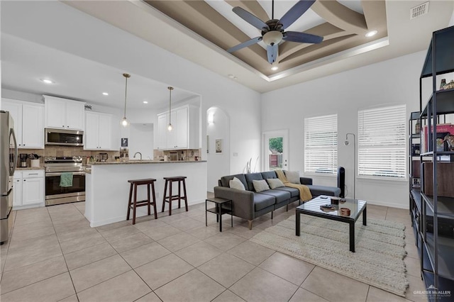 3604 Illeana St, Edinburg, TX 78539 - living area featuring light tile patterned floors, a ceiling fan, recessed lighting, a tray ceiling, and arched walkways