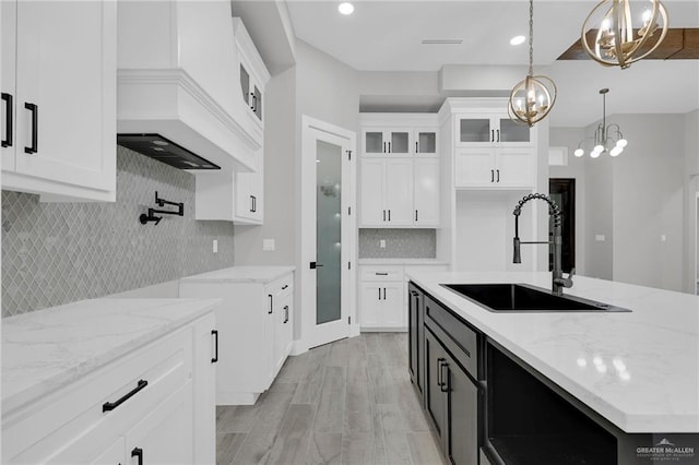 1809 W Hayes Ave, Alton, TX 78573 - kitchen featuring a sink, a chandelier, backsplash, white cabinets, and glass insert cabinets