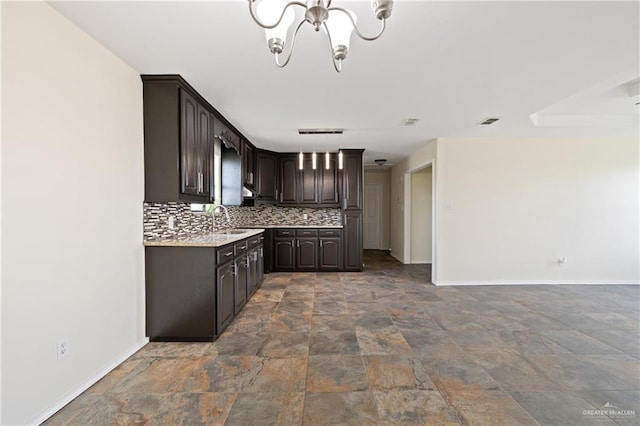 kitchen featuring dark brown cabinets, sink, backsplash, and an inviting chandelier