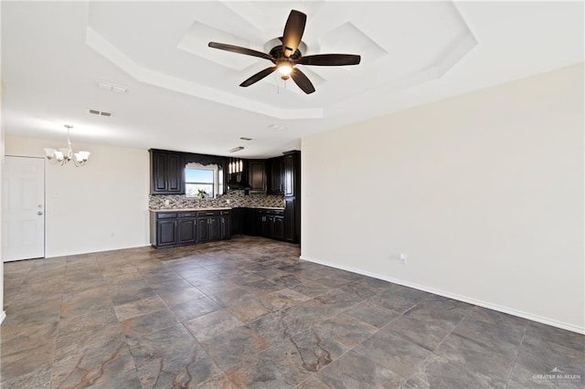 unfurnished living room with a tray ceiling and ceiling fan with notable chandelier