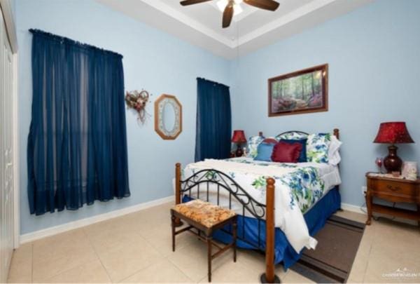 bedroom with tile patterned flooring, a raised ceiling, and ceiling fan