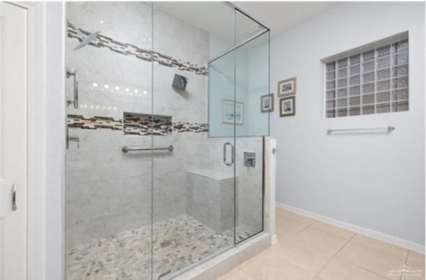 bathroom with a shower with door and tile patterned flooring