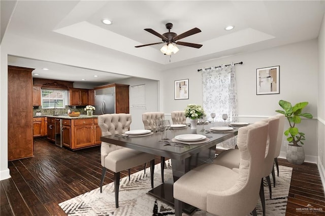 dining room featuring baseboards, dark wood-style flooring, a raised ceiling, and recessed lighting