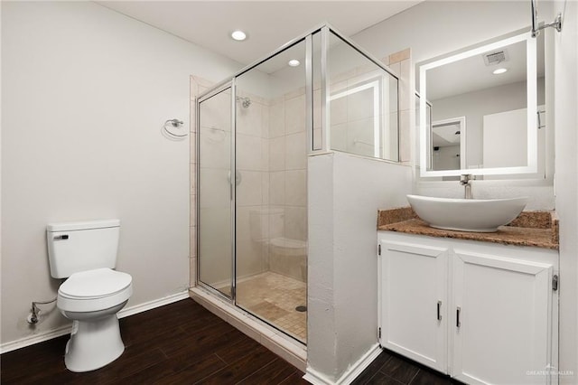 bathroom featuring toilet, wood finished floors, a shower stall, and visible vents