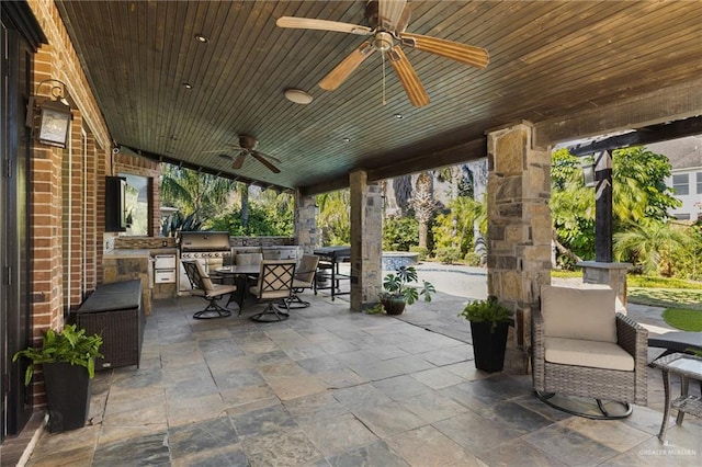 view of patio featuring exterior kitchen, outdoor dining area, a grill, and a ceiling fan