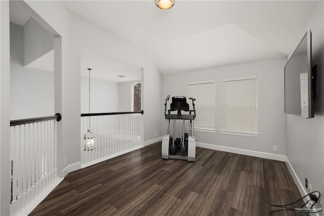 workout area featuring lofted ceiling, wood finished floors, and baseboards