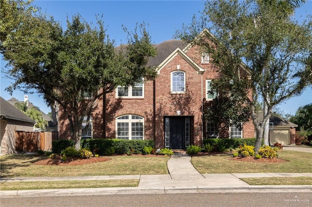 view of front of home with a garage, a front yard, brick siding, and fence