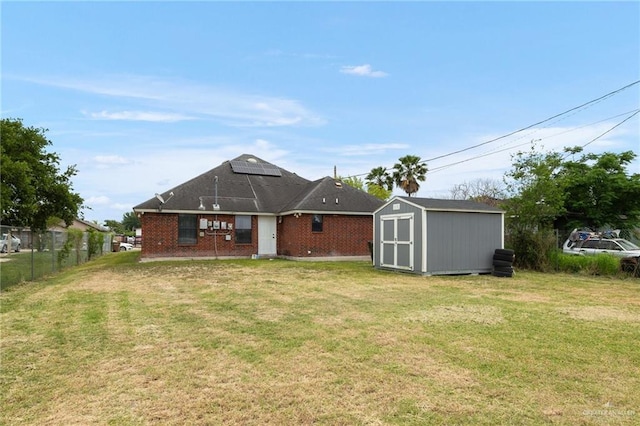 3417 N Pablo St N, Edinburg, TX 78541 - rear view of house featuring a storage shed, an outbuilding, fence, a lawn, and roof mounted solar panels