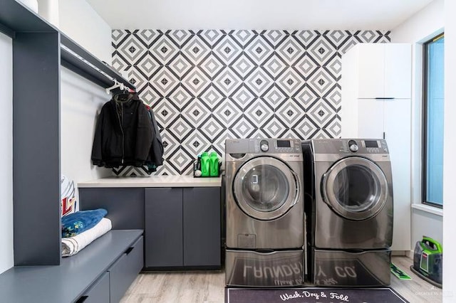 clothes washing area featuring cabinets, light hardwood / wood-style flooring, and washer and dryer