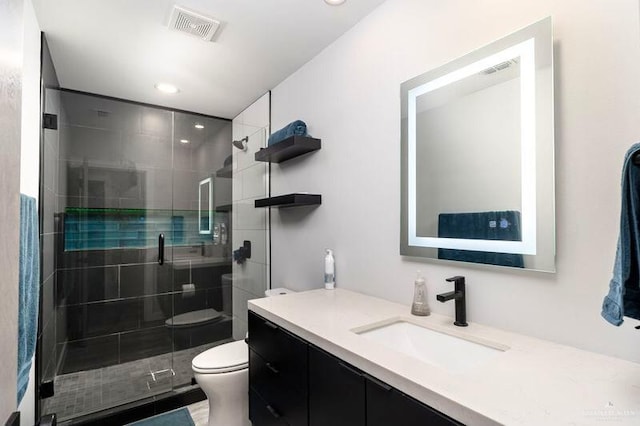 bathroom with a shower with door, vanity, and toilet