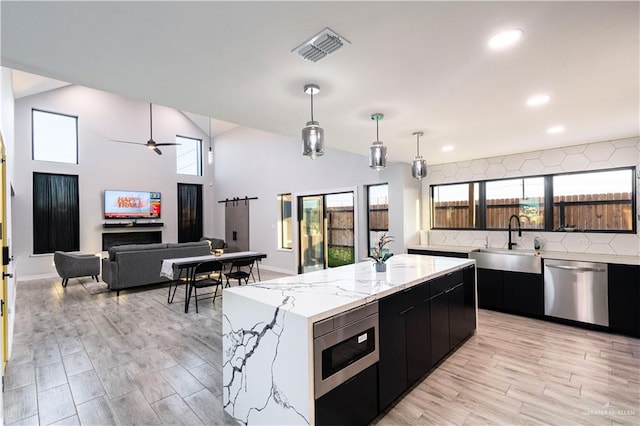 kitchen featuring appliances with stainless steel finishes, ceiling fan, sink, decorative light fixtures, and a kitchen island