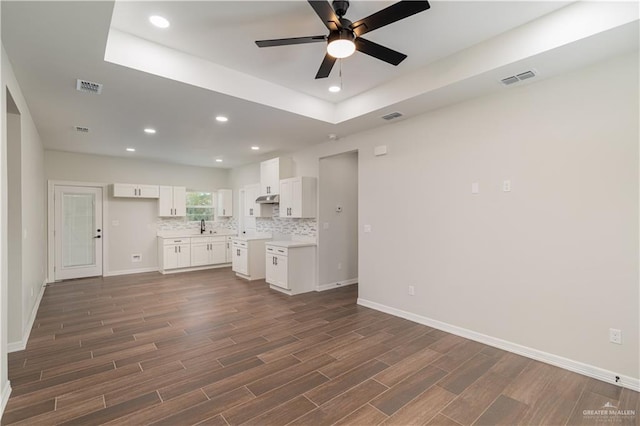 kitchen featuring white cabinetry, sink, ceiling fan, dark wood-type flooring, and a raised ceiling