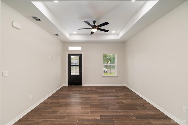 entrance foyer with ceiling fan, dark wood-type flooring, and a tray ceiling