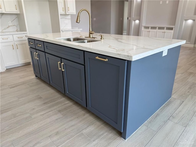 1203 Moses Dr, San Juan, TX 78589 - kitchen with a kitchen island with sink, white cabinetry, light wood-style floors, and a sink
