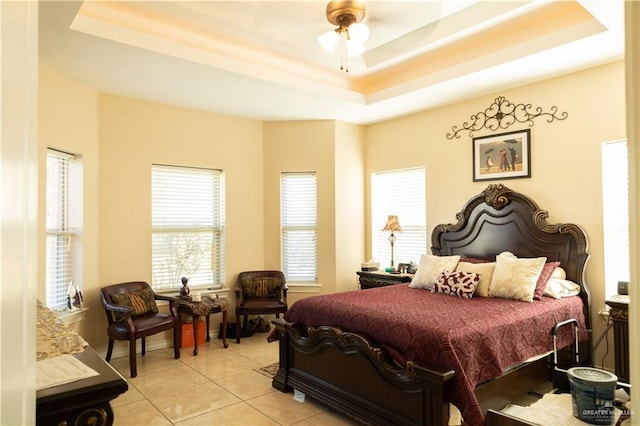 bedroom featuring light tile patterned floors, a tray ceiling, and a ceiling fan