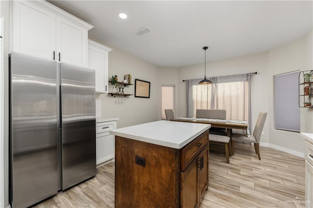 kitchen featuring white cabinetry, built in fridge, pendant lighting, and light hardwood / wood-style floors