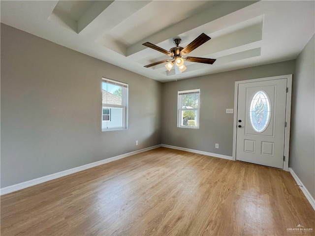 foyer entrance with light hardwood / wood-style flooring, a raised ceiling, and ceiling fan