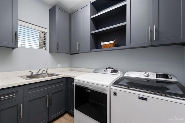 laundry area with cabinets, separate washer and dryer, sink, and light wood-type flooring