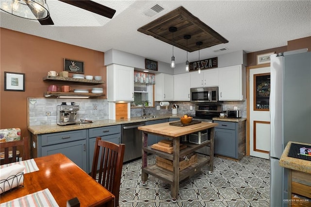 1813 Tyler St, Mission, TX 78572 - kitchen with stainless steel appliances, white cabinets, decorative backsplash, open shelves, and ceiling fan
