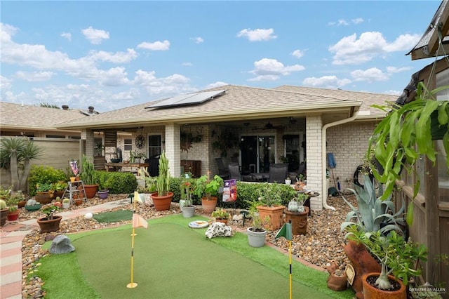 1813 Tyler St, Mission, TX 78572 - back of property featuring ceiling fan, a putting green, brick siding, solar panels, and roof with shingles
