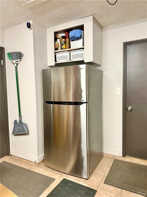1813 Tyler St, Mission, TX 78572 - kitchen featuring freestanding refrigerator, light tile patterned flooring, and a textured ceiling