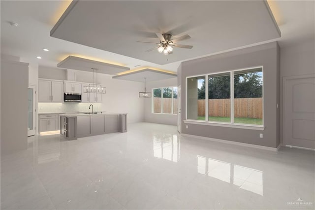 unfurnished living room with ceiling fan with notable chandelier and sink