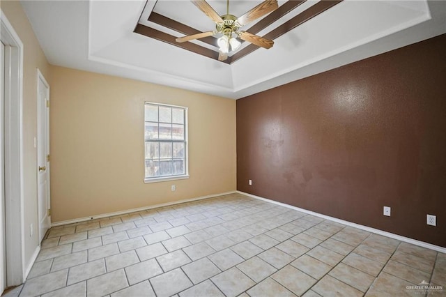 tiled empty room with a tray ceiling and ceiling fan