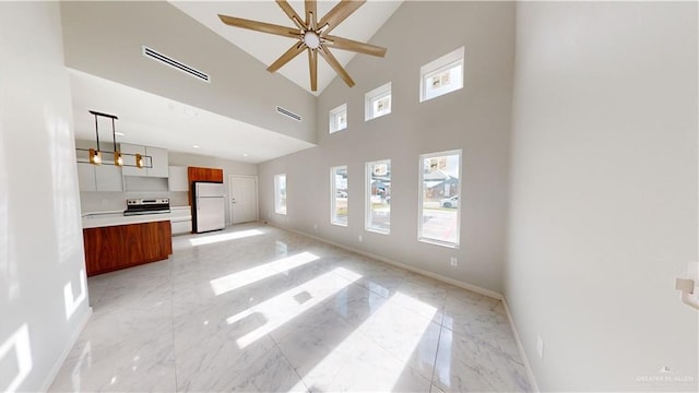 unfurnished living room featuring ceiling fan and a high ceiling