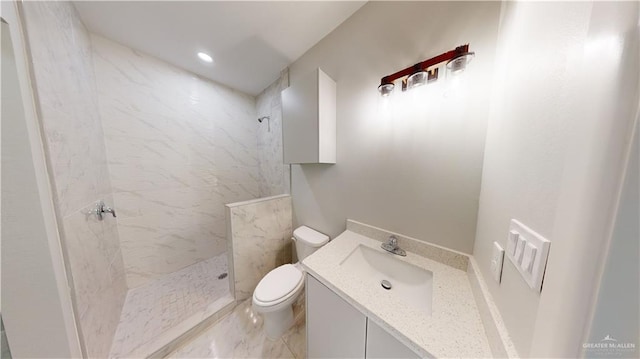 bathroom featuring vanity, a tile shower, and toilet