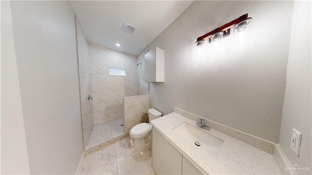 bathroom featuring vanity, tiled shower, and toilet