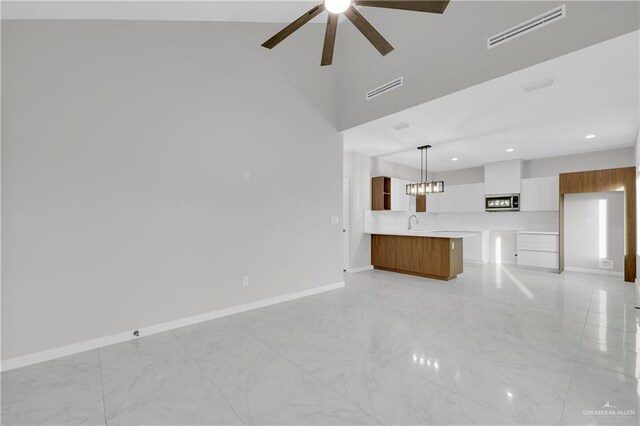 unfurnished bedroom with ceiling fan, ensuite bath, and a tray ceiling