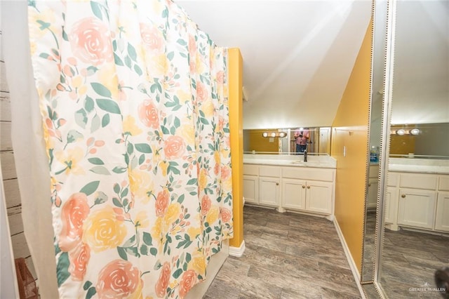 bathroom with hardwood / wood-style flooring, vanity, and lofted ceiling