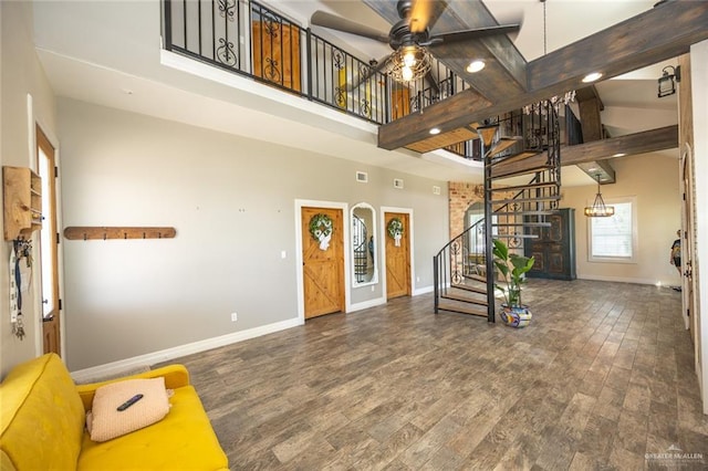 entrance foyer with hardwood / wood-style flooring, ceiling fan, beam ceiling, and a high ceiling