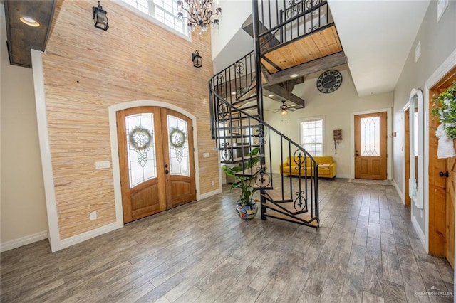 entryway with hardwood / wood-style flooring, a chandelier, high vaulted ceiling, and french doors