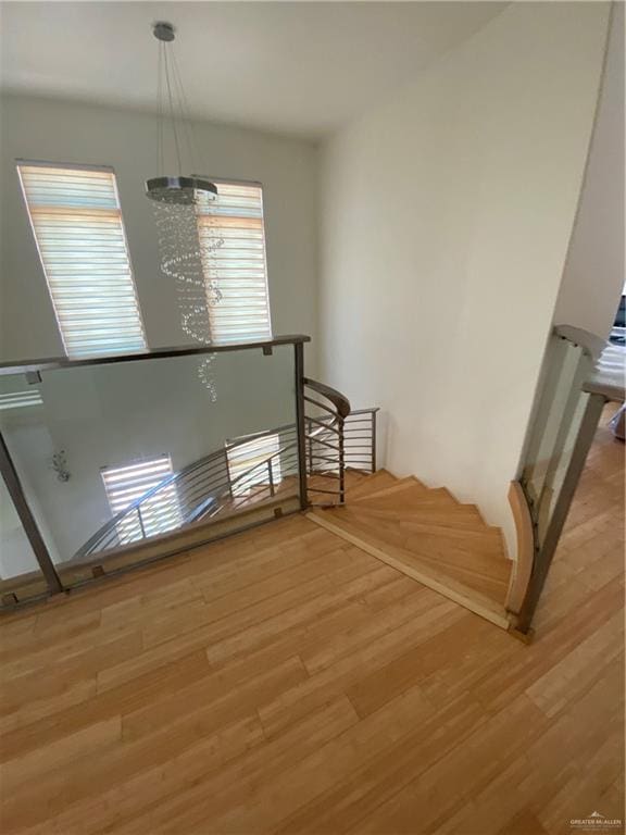 stairs featuring hardwood / wood-style floors and a chandelier