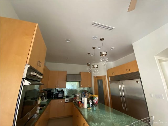 kitchen featuring pendant lighting, wall chimney range hood, and appliances with stainless steel finishes