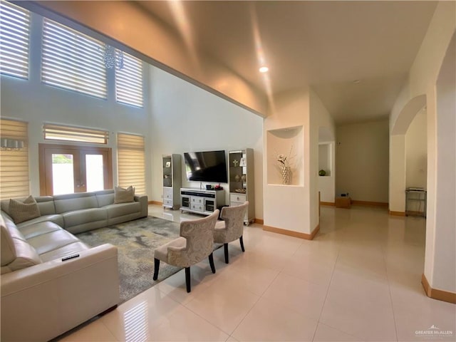 living room featuring light tile patterned floors, a towering ceiling, and french doors