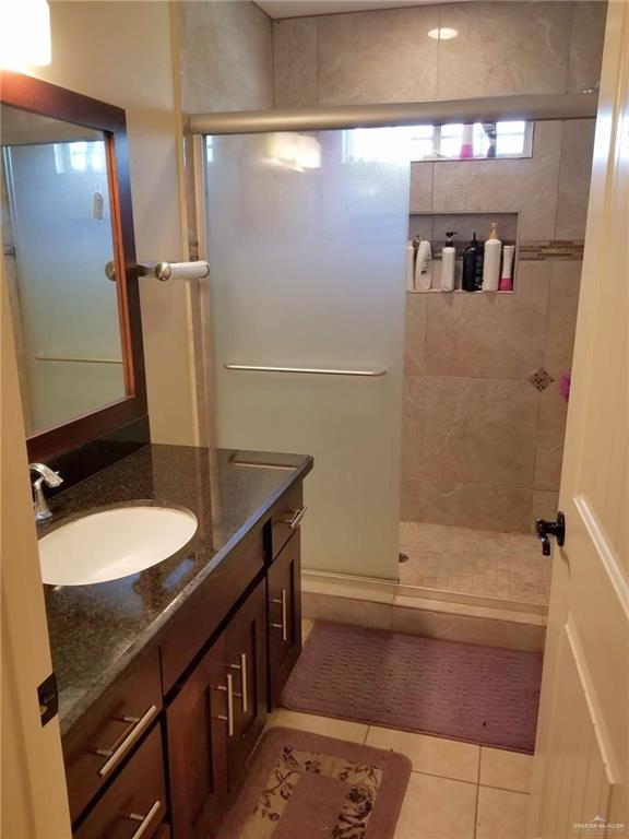 bathroom featuring tile patterned flooring, vanity, and walk in shower