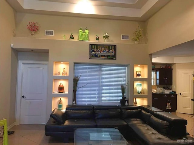 living room featuring built in shelves, light tile patterned floors, and a high ceiling