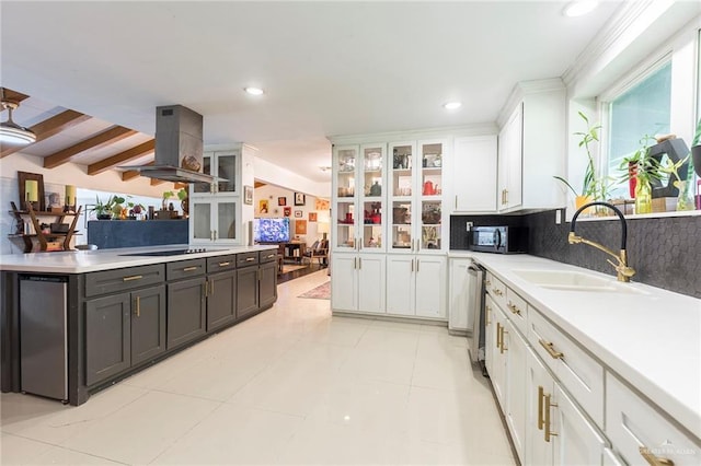 kitchen featuring appliances with stainless steel finishes, island exhaust hood, light countertops, white cabinetry, and a sink