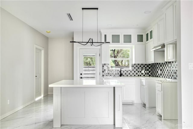 kitchen with white cabinets, pendant lighting, a center island, and decorative backsplash