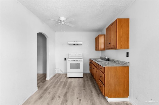 kitchen with a ceiling fan, white electric stove, brown cabinetry, arched walkways, and a sink