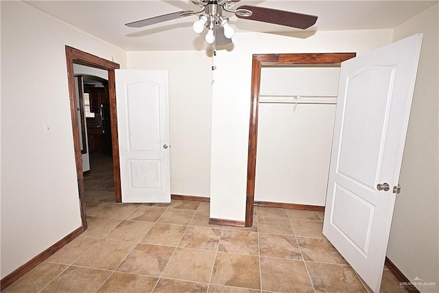 unfurnished bedroom featuring light tile patterned floors, arched walkways, a closet, a ceiling fan, and baseboards