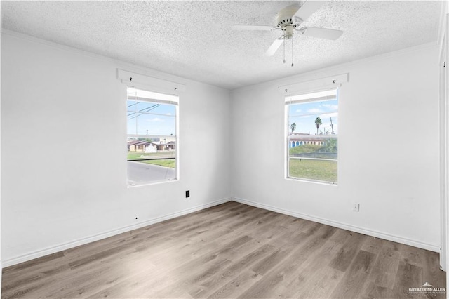 spare room featuring a textured ceiling, wood finished floors, ceiling fan, and a wealth of natural light