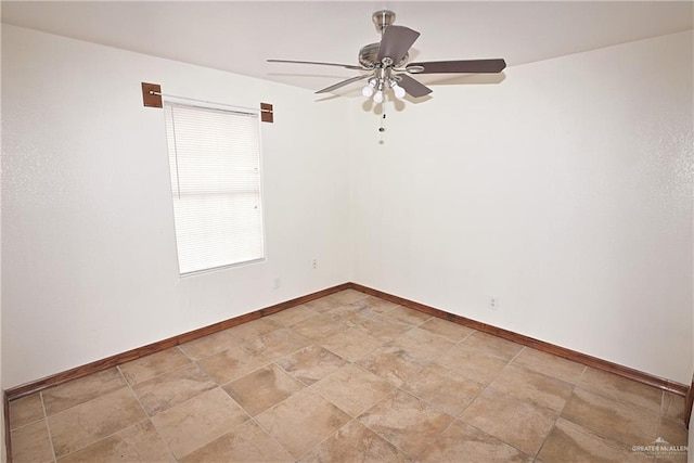 unfurnished room with stone finish flooring, baseboards, and a ceiling fan