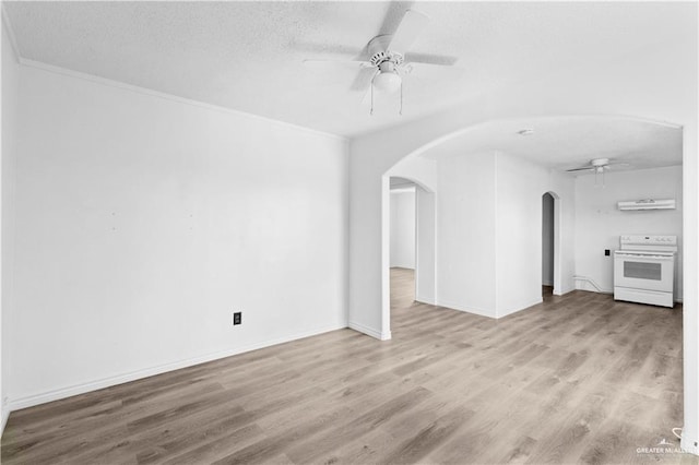 unfurnished living room with baseboards, arched walkways, a ceiling fan, a textured ceiling, and wood finished floors