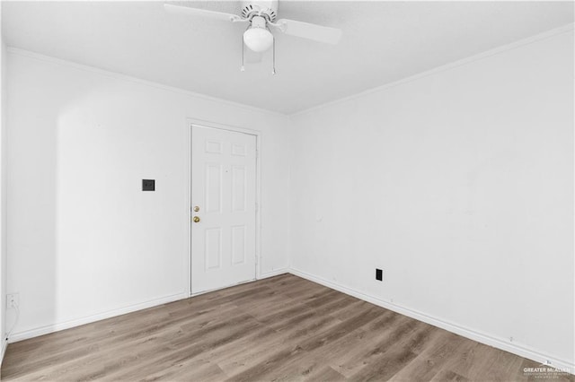 spare room featuring crown molding, ceiling fan, wood finished floors, and baseboards