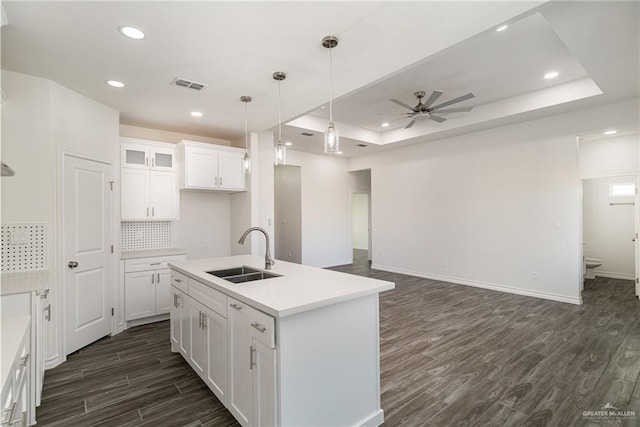 kitchen featuring dark wood-type flooring, a sink, visible vents, white cabinets, and a tray ceiling