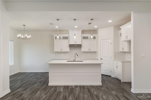 kitchen with dark wood-style flooring, light countertops, glass insert cabinets, white cabinets, and a sink